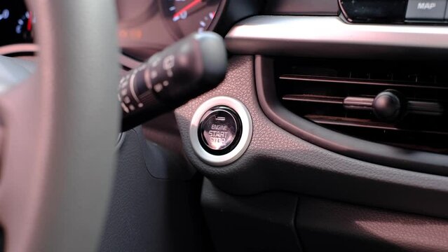 Male hand presses the start button in the car close-up.