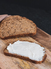 Pieces of bread with cheese cream on a board on the table.
