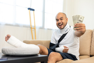 Happy man pay money medical expenses from accident fracture broken bone injury with leg splints in...