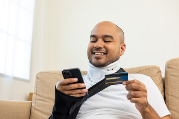 Happy man using credit card pay medical expenses from accident fracture broken bone injury with leg splints in cast neck splints collar sling support arm. Social security and health insurance.
