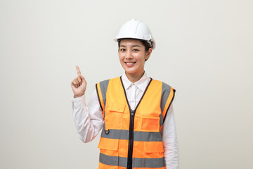 Asian engineer worker woman or architect with white safety helmet standing on isolated white background. Mechanic service factory Professional work job occupation in uniform pointing finger to space
