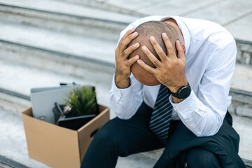Sadness depressed Businessman with box cardboard packing personal items after losing jobs. Failure businessman sitting at stair front of building. Your fired Unemployed Jobless People Crisis