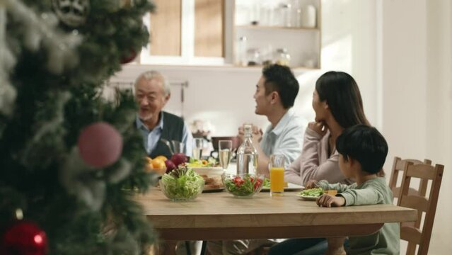 happy three generation asian family eating meal chatting talking at home on christmas day