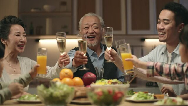 happy multi generation asian family toasting to celebrate holiday during dinner at home