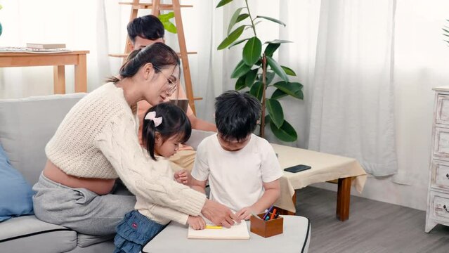 4K, Beautiful Asian pregnant mother, She sat and painted with her daughter and son, It is a leisure activity on weekends children, father sitting in back looked at three of them, and smiled happily.