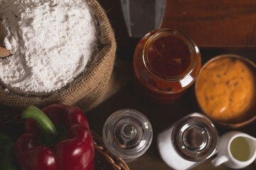 Bag with flour and wooden scoop on a wooden table in a rustic kitchen. Top view the ingredients for homemade pizza on wooden table.