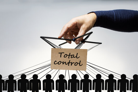 Manipulation and brainwash concept. Male hand, puppeteer controls the paper figures of people with strings.