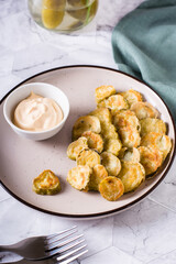 Fried pickles appetizer and sauce in a bowl on a plate. Homemade snack. Vertical view