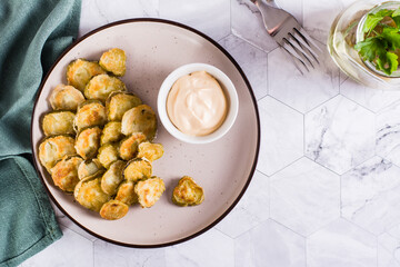 Fried pickles and sauce on a plate. American snack. Top view.