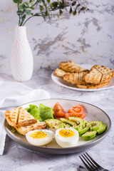 Sliced avocado, soft boiled egg, tomatoes and toast on a plate. Homemade breakfast. Vertical view