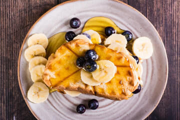 Banana, blueberry and honey toasts on a plate. Homemade dessert. Top view. Closeup
