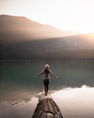 girl standing by a lake looking at sun rays