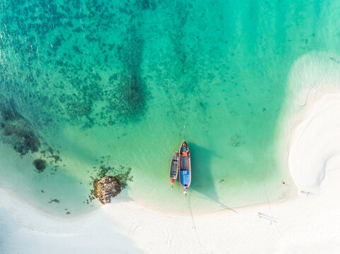 Aerial top view with white sand beah  and the  local boat near the lagoon seashore as the tropical island background