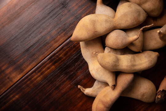 Tamarind fruit (Tamarindus indica) on wooden rustic table. Tropical fruit highly appreciated in several countries of the world. Closeup image.