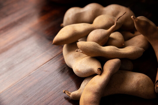 Tamarind fruit (Tamarindus indica) on wooden rustic table. Tropical fruit highly appreciated in several countries of the world. Closeup image.