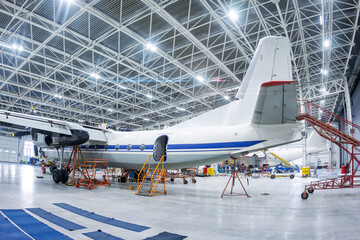 Transport turboprop aircraft in the hangar. Airplane under maintenance. Checking mechanical systems for flight operations