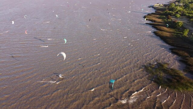 Group of kitesurfers kitesurfing on Rio de la Plata river at sunset, Vicente Lopez area park of Buenos Aires in Argentina. Aerial drone view