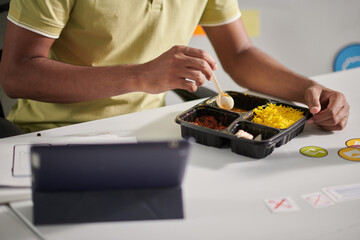 Indian UX designer eating curry rice at his office table and choosing icons for project