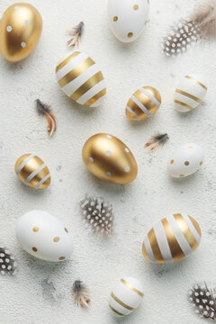 Easter eggs are painted with gold paint on a gray concrete  background.