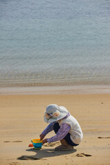 Obraz premium 冬の海岸のビーチで砂遊びしている小学生の女の子の様子