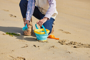 冬の海岸のビーチで砂遊びしている小学生の女の子の様子