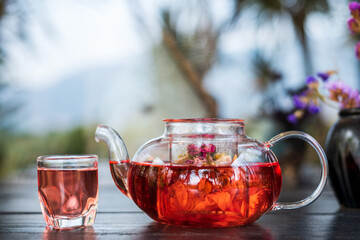 Rose buds tea, tea cup, strainer and glass jar with rose, Cup of freshly brewed fruit and herbal tea, Hot water is poured from the kettle into a cup with tea leaves.