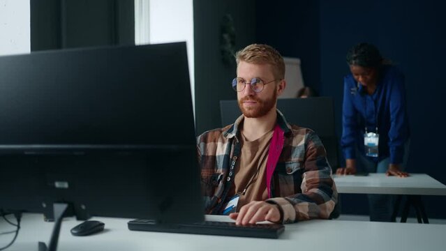 male programmer or technician of tech support in IT company, portrait of man at table with computer