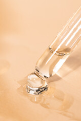 Flowing essential oil, serum from a glass dropper on a beige background. Means for massage, spa and body care.