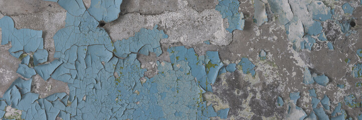 Peeling paint on the wall. Panorama of a concrete wall with old cracked flaking paint. Weathered rough painted surface with patterns of cracks and peeling. Wide panoramic texture for grunge background