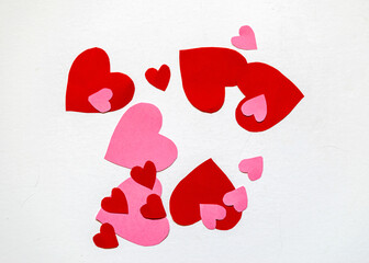 Red and pink paper hearts of different sizes on a light background, celebration of love, Valentine's day concept