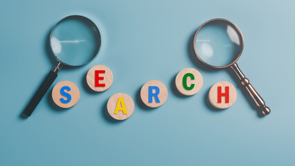Magnifying glass and wooden block on blue background,Keyword search concept to find information...