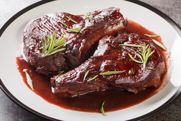Drunken Pork Chops with red wine sauce and herbs closeup on the plate on the table. Horizontal