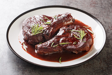 Maiale ubriaco is a traditional Tuscan dish simmered pork chops with red wine closeup on the plate on the table. Horizontal