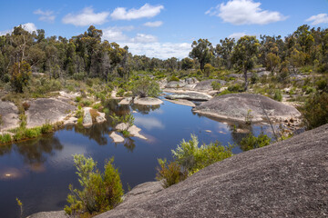 Fototapeta na wymiar Creek flowing gently through granite rocks and vegetation