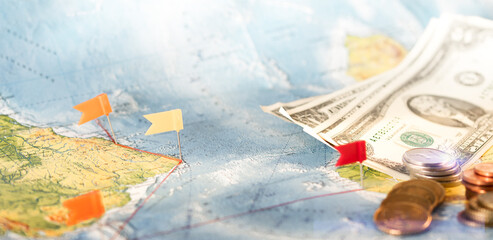 Fototapeta na wymiar Thumb tacks in a world map, cash and coins.