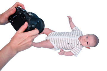 A photographer takes pictures of a newborn baby with a camera in studio, isolated on a white background. Photo session of children in the studio. Kid aged two months