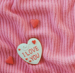 A heart-shaped cookie with the I love you inscription on a pink background. Top view