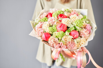 Florist woman creates beautiful bouquet of mixed flowers with varietal carnations, peony and eustoma. European floral shop concept. Handsome fresh bunch. Education, master class and floristry courses