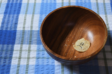 Sad face on last potato chip brown wooden bowl side lighting moody shadows creating a sense of...