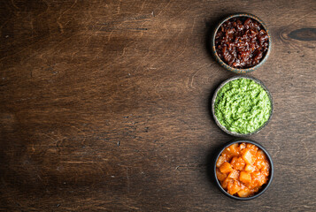 Set of indian chutneys in bowls on wooden background, top view, copy space