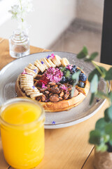 Waffle with almonds, blueberries, strawberries and bananas with honey and a fresh juice