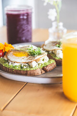 Avocado and egg toast with bean sprouts on a white plate in a breakfast restaurant. Vegetarian and healthy food