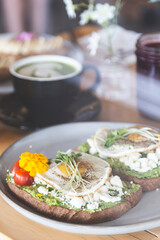 Avocado and egg toast with bean sprouts and tomatoes on a white plate in a breakfast restaurant. Vegetarian and healthy food.