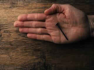 Hand with an old rusty nail symbolizes the crucifixion of Jesus. Easter concept