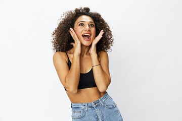 Beautiful woman with curly afro hair posing on a white isolated background smile happiness in jeans and black top emotion, hand signs, copy space