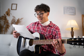 Man with guitar holding music book with notes at home have an idea.