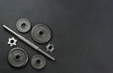 Disassembled metal dumbbell lies on an empty concrete background. copy space, top view