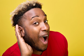 Close-up of a cheerful black guy listening overhearing eavesdropping with his ear secret...