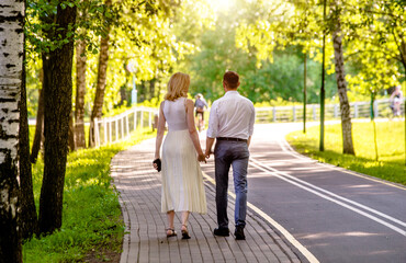 Fototapeta premium A guy and a girl walk along the path in the city Park 