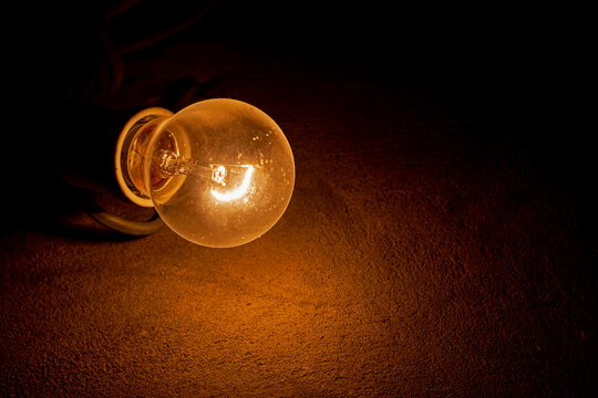 weakly burning electric light bulb in the dark near the wall. blackout, bomb shelter.